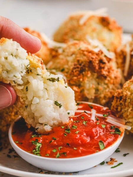 Air Fryer Arancini Rice Balls being dipped into red sauce