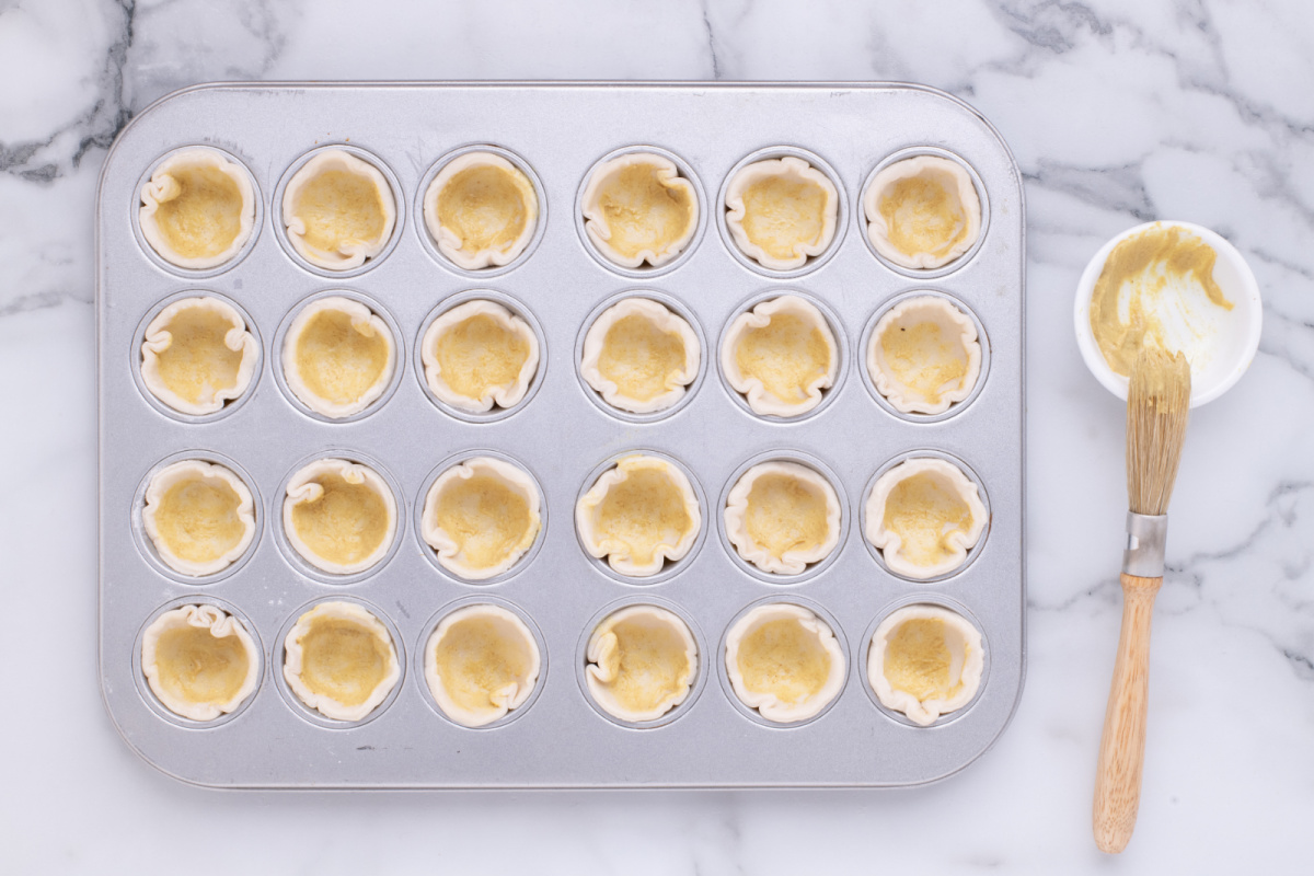 Brush mustard into batter cups in muffin pan